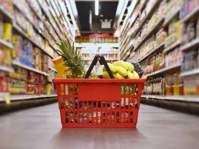 Full grocery basket sitting on the floor in the middle of a isle in a grocery store.