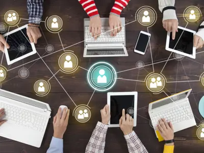 Photo from above of people sitting around in a meeting using technology