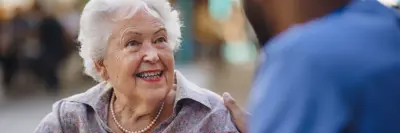 Senior woman smiling to a worker at long term care home.