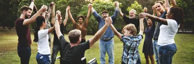 Group of people holding hand together in the park.
