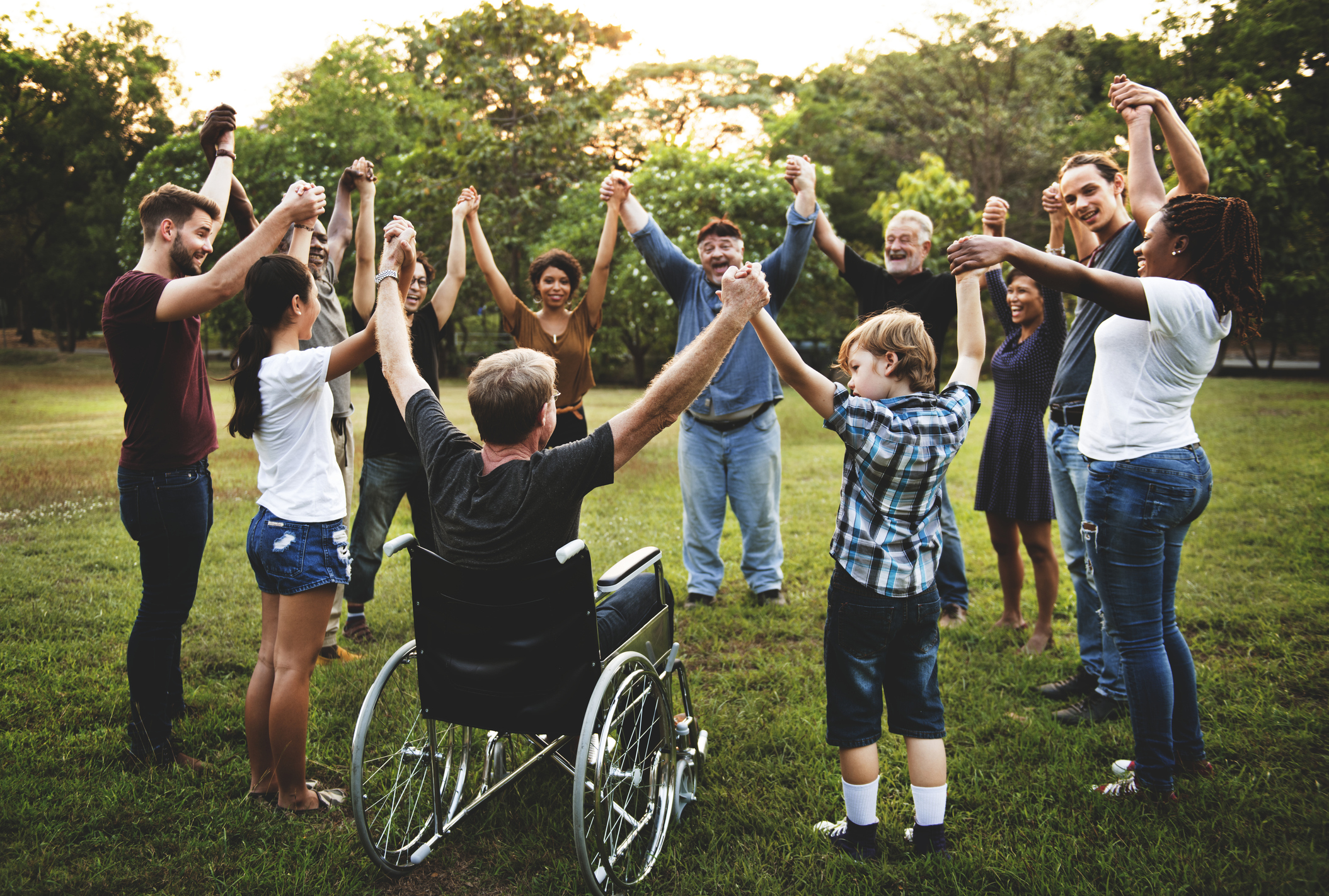 Group of people holding hand together in the park.