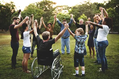 Group of people holding hand together in the park.
