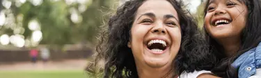 Woman with a child on her back both smiling and happy